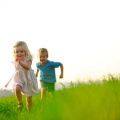 Young siblings running in field