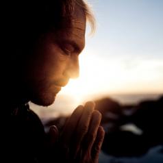 A man prays at sunset