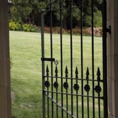 An iron gate opens onto a grassy scene.