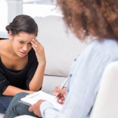 A young woman with a sad look on her face talks to her therapist.