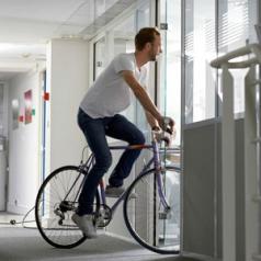 A man rides a bicycle through an office.