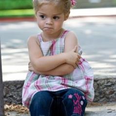 Angry toddler sitting with arms crossed