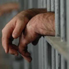Hands resting on prison bars