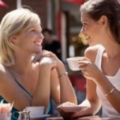 Two women laughing and having tea at a café