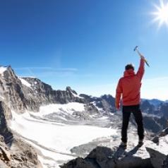 Man with ice axe on top of a mountain