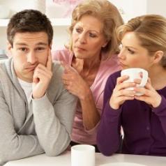 Woman looking at husband while her mother scolds him