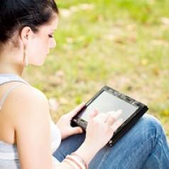 Woman with tablet leaning against tree