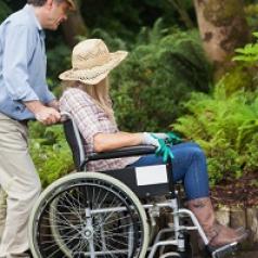man-pushing-wife-in-wheelchair-through-garden