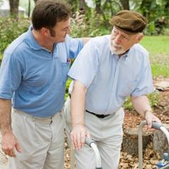 male caregiver walks with elderly man