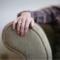 aging woman with hand resting on couch armrest