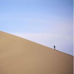 man hiking up sand dune