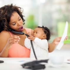woman on phone while holding baby