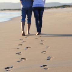 Couple walks arm-in-arm on the beach