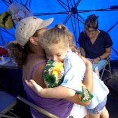 A woman hugs a child in a disaster relief tent