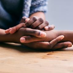 Cropped shot of a two people holding hands in comfort on a table