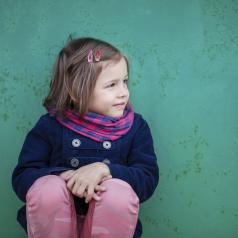 Portrait of preschooler girl sitting near wall