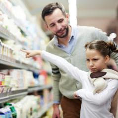 Child and parent grocery shop while child is upset over not getting requested item
