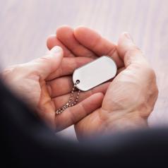 Hands hold a dogtag