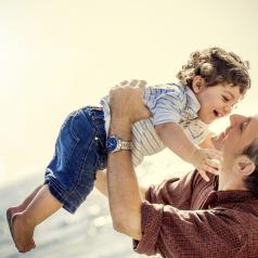 A smiling father holds his son up in the air