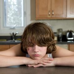 teen rests chin on layered hands on kitchen counter