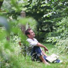 Man relaxing with book in countryside