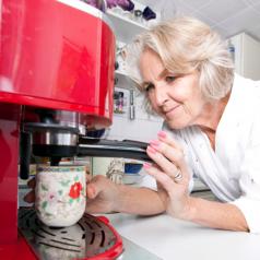 Senior woman makes a cup of coffee at home