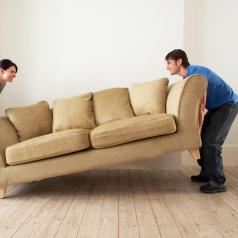 Two people moving a sofa together