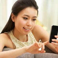 Young Woman Using Mobile Phone On Sofa At Home