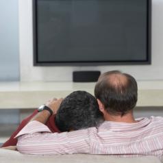 Couple Sitting on Sofa with Television Off