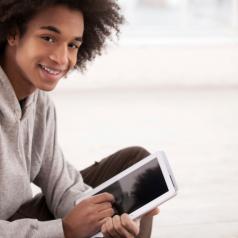 Young man looks up smiling from tablet pc