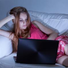 Teen girl using laptop on couch at night