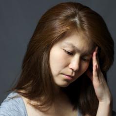 Asian woman with headache thinking