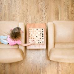 A girl plays chess alone next to empty chair