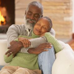 Senior African couple hugging on the sofa