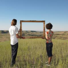 A man and woman hold up a frame together in a field