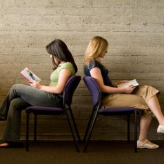 Two women read books, facing away from each other.