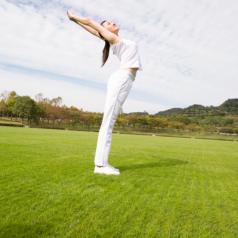 A woman does yoga stretches in a field