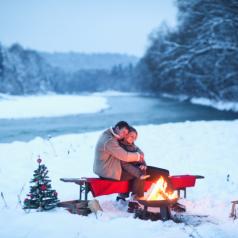 Couple sitting bycampfire in snow