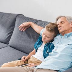 Grandfather and grandson sleep on sofa