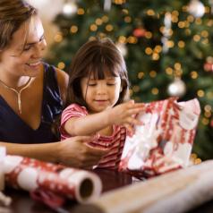 Mother and daughter opening presents by tree
