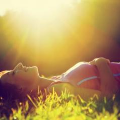 Young woman lying on the grass at summer sunset