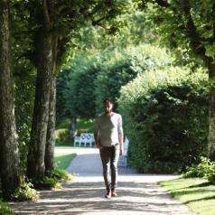A man walks along a tree-lined path