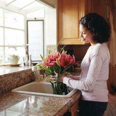 A woman holds pink lilies over a sink