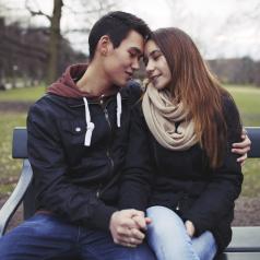 Teen couple holding hands and cuddling on bench