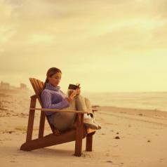 Reading in chair on beach at sunset