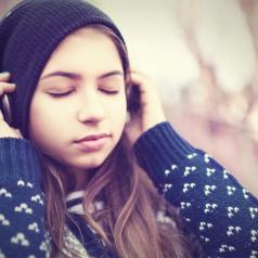 Teenage girl wearing headphones with eyes closed