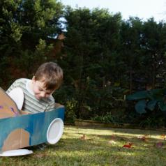 Boy plays in car made from box and paper plates
