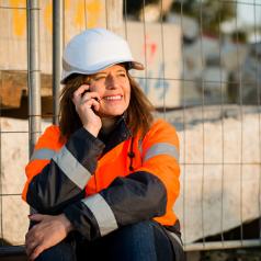 Smiling construction worker using phone on break