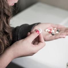 Girl holding several different pills in her hand