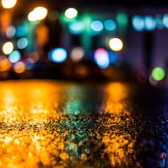 Rain-soaked street with blurred lights in the background